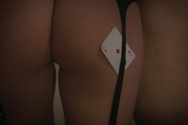 Playing card held between womans suspenders over her bottom, during romantic couple sex.