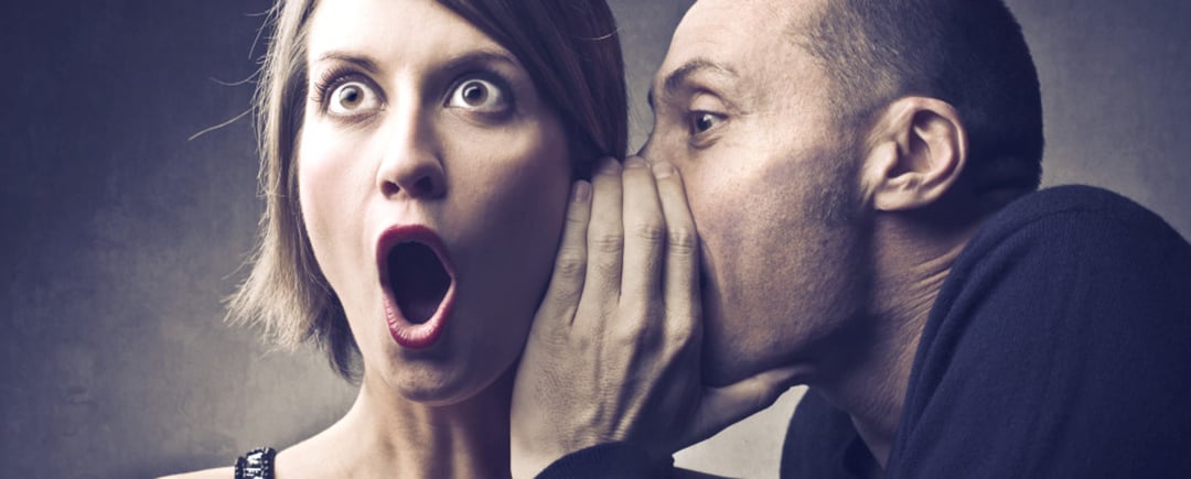 Person whispering some dirty talk into the ear of a surprised woman