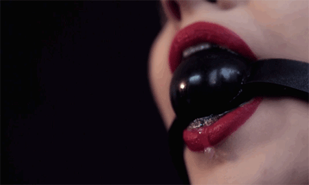Close up of woman's mouth with ball gag in some soft kink and BDSM play